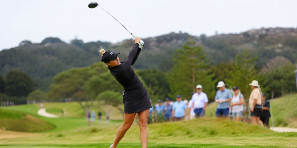 Woman swinging a golf club on a golf course